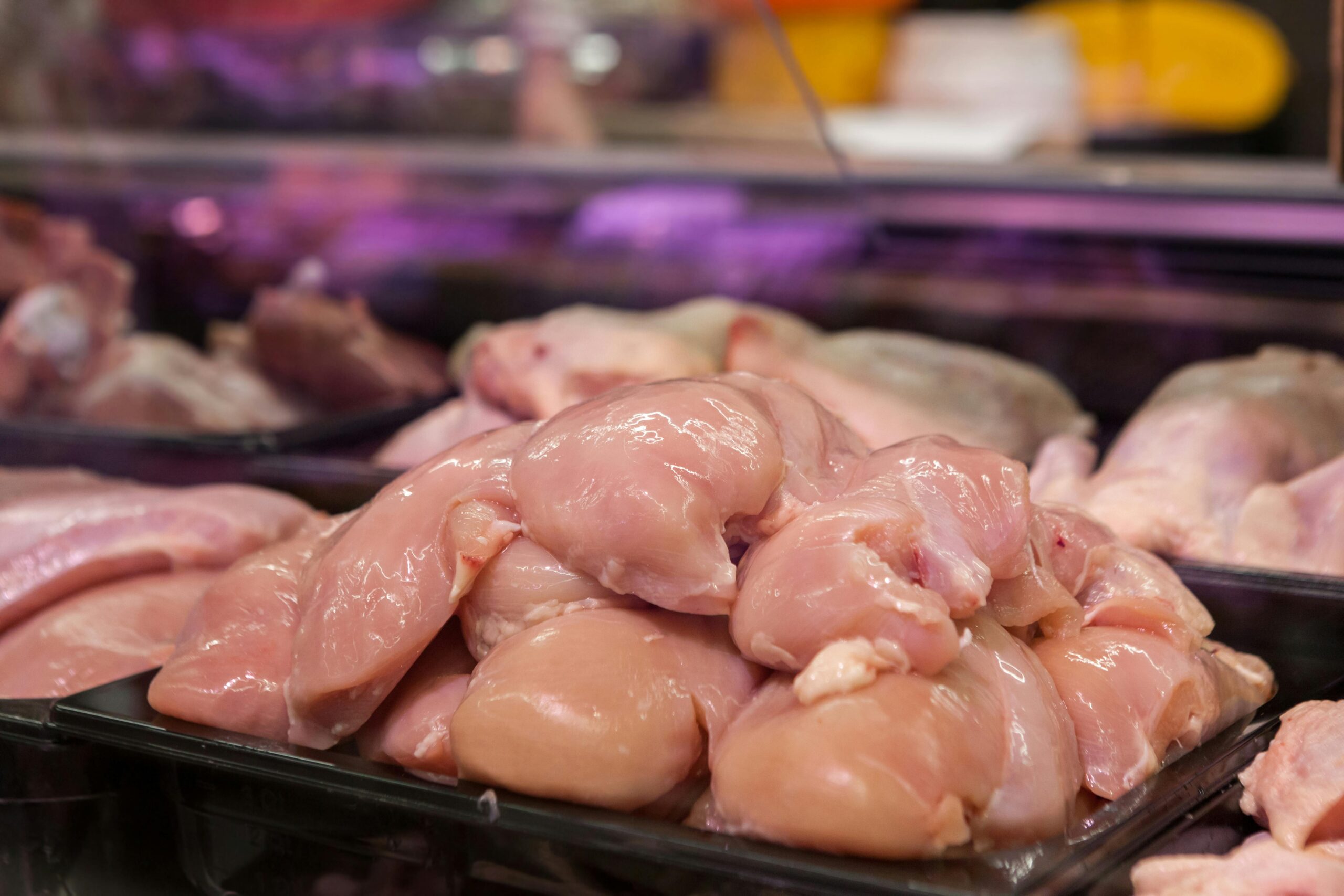 Fresh raw chicken breasts displayed in a supermarket setting, ready for purchase.